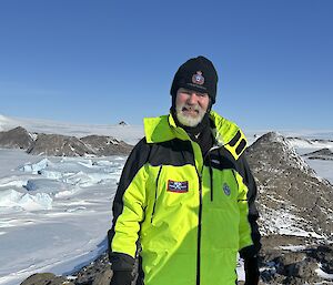 Dominik in a lime green jacket standing on a snow covered mountain top