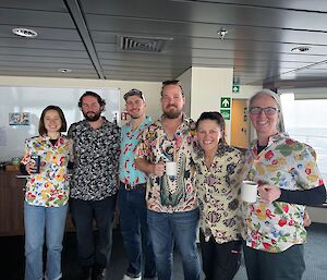 Six people in crazy coloured shirts standing on the observation deck