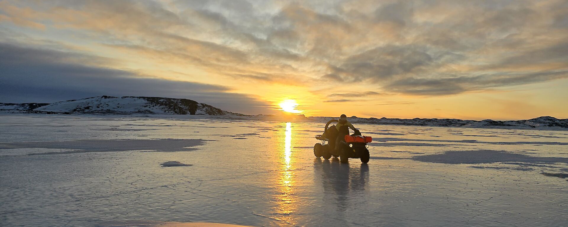vehicle on sea ice with sunset in background