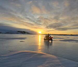vehicle on sea ice with sunset in background
