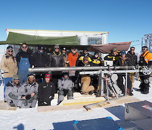 A group of people standing alongside a long, horizontal ice core drill.