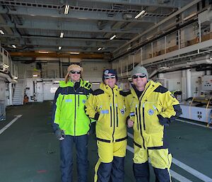 Two men and a woman standing in a helicopter hangar