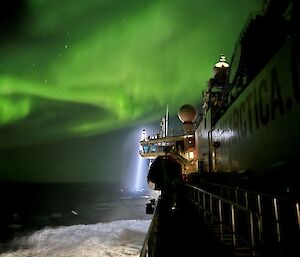 Green shimmering light above a ship in a wild ocean