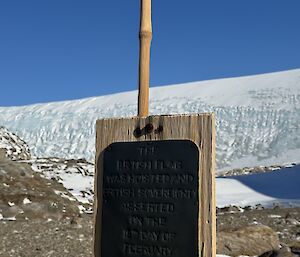A metal sign attached to a piece of wood on a bamboo pole