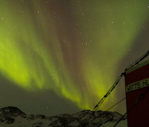 Green aurora in the sky with a hut in the foreground