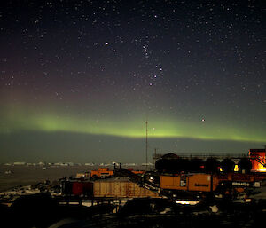 A green aurora in the night sky over Davis station