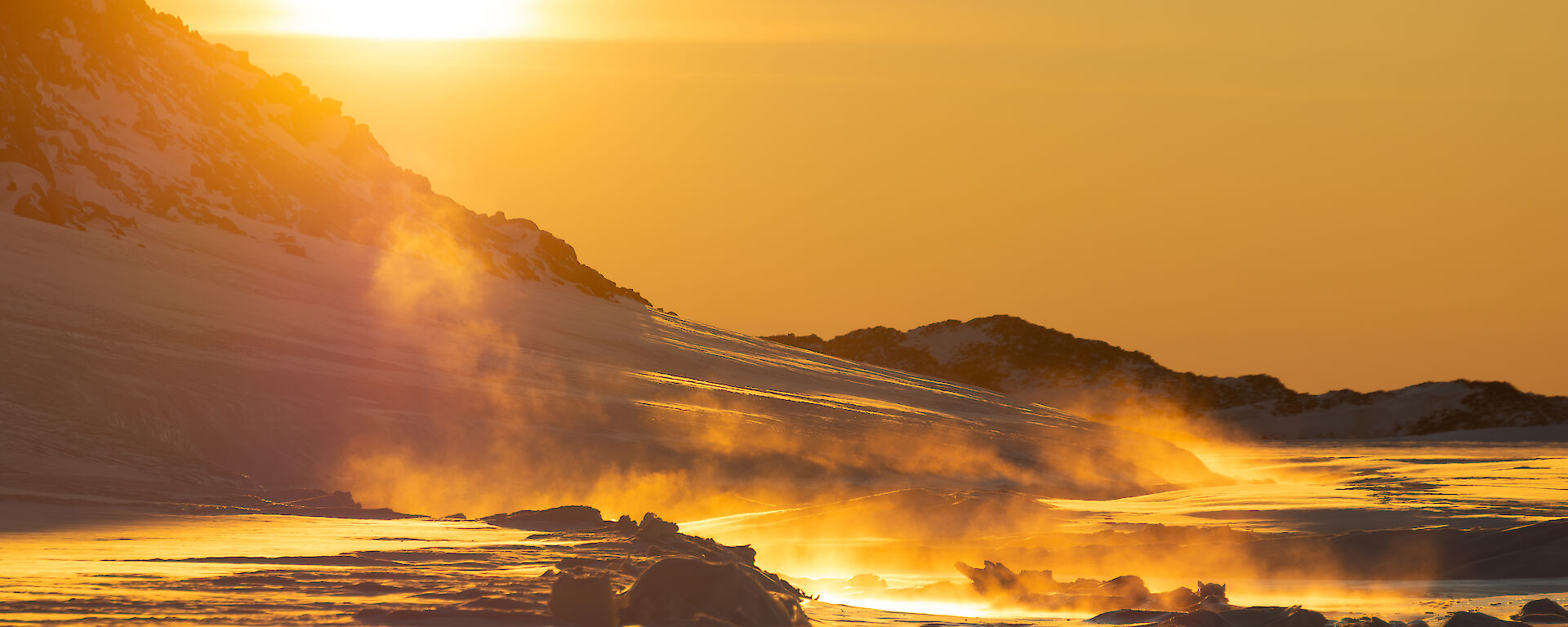 A golden sunset over ice, with an icy mist rising from the ground