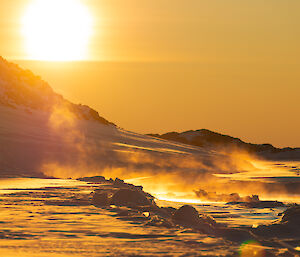 A golden sunset over ice, with an icy mist rising from the ground