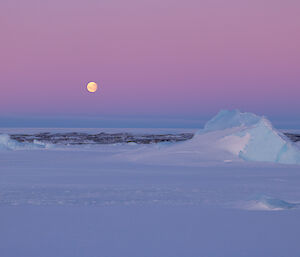 Moon in background near iceberg