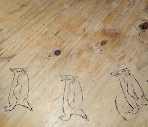 Engravings of penguins on a wooden table-top