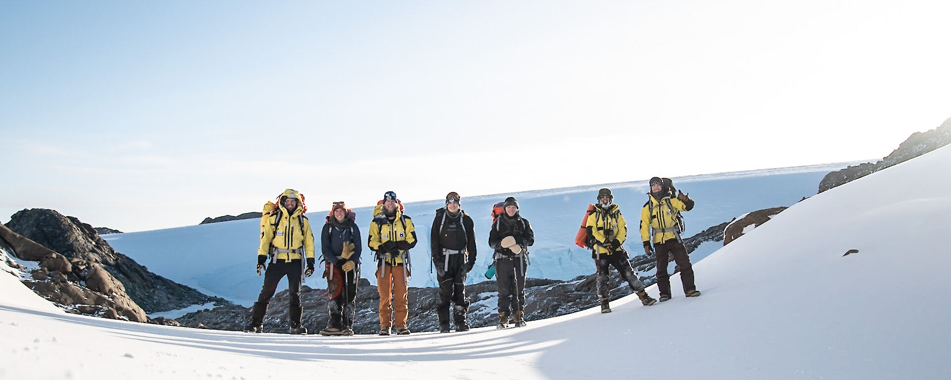 A group of expeditioners standing in a line on an ice slope