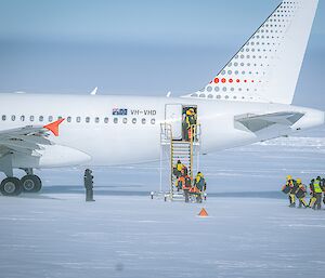Expeditioners ascend the stairs of an A319 aircraft in Antarctica