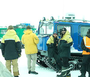 Expeditioners standing amongst a fleet of Hagglunds