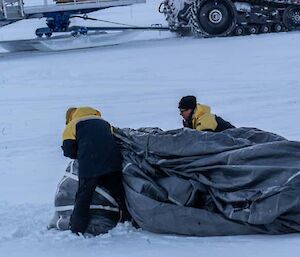 Two expeditioners fodling up a parachute.