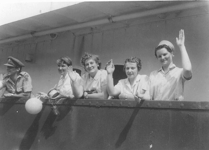 Four women wave from farewell from a ship.