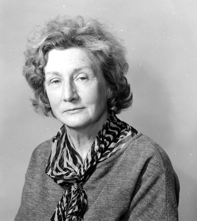 Black and white portrait of a woman with light coloured short hair, wearing a scarf with a ripple pattern.