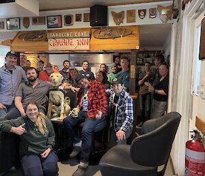 A group of over twenty people gather around Stay, the Tasmanian Guide Dog's collection dog to celebrate her finding. The group is gathered around a bar and Stay sits atop the bar.