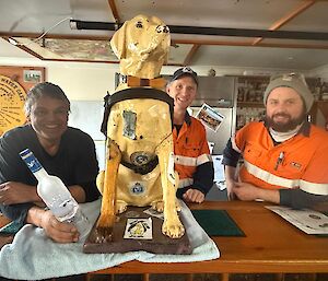 Stay, the Tasmanian Guide Dog's collection dog sits on a bar surrounded by three smiling men