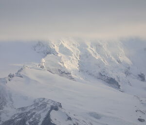 A snowy mountain topped with cloud