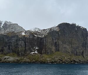 Black rock cliffs with snow on the top