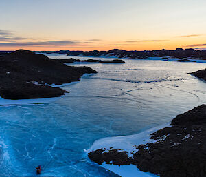 Looking over a frozen fjord in dim light with a sunset on the horizon