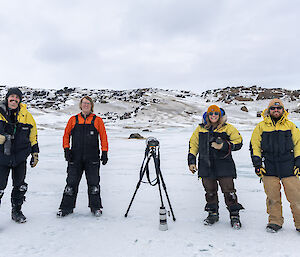 Four people standing on ice with cameras.