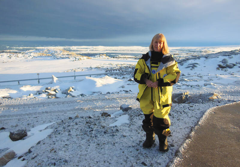 A women in yellow Antarctic clothing in a snow-covered landscape