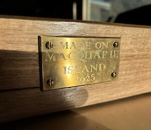 A brass plaque engraved with the words, "Made on Macquarie Island 2025".