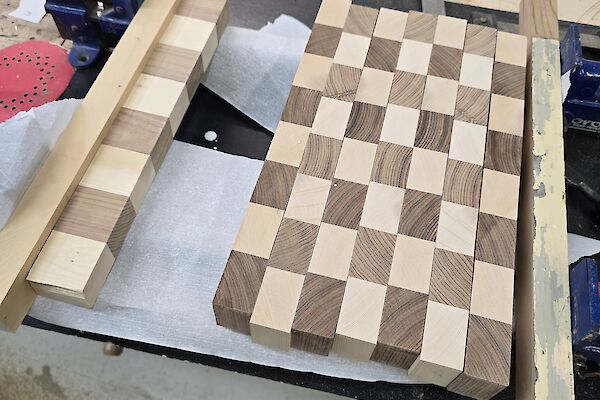 Squares of light and dark wood laid out to start the assembly of a chessboard