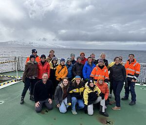 A group of smiling people posing for a photo on a helicopter deck