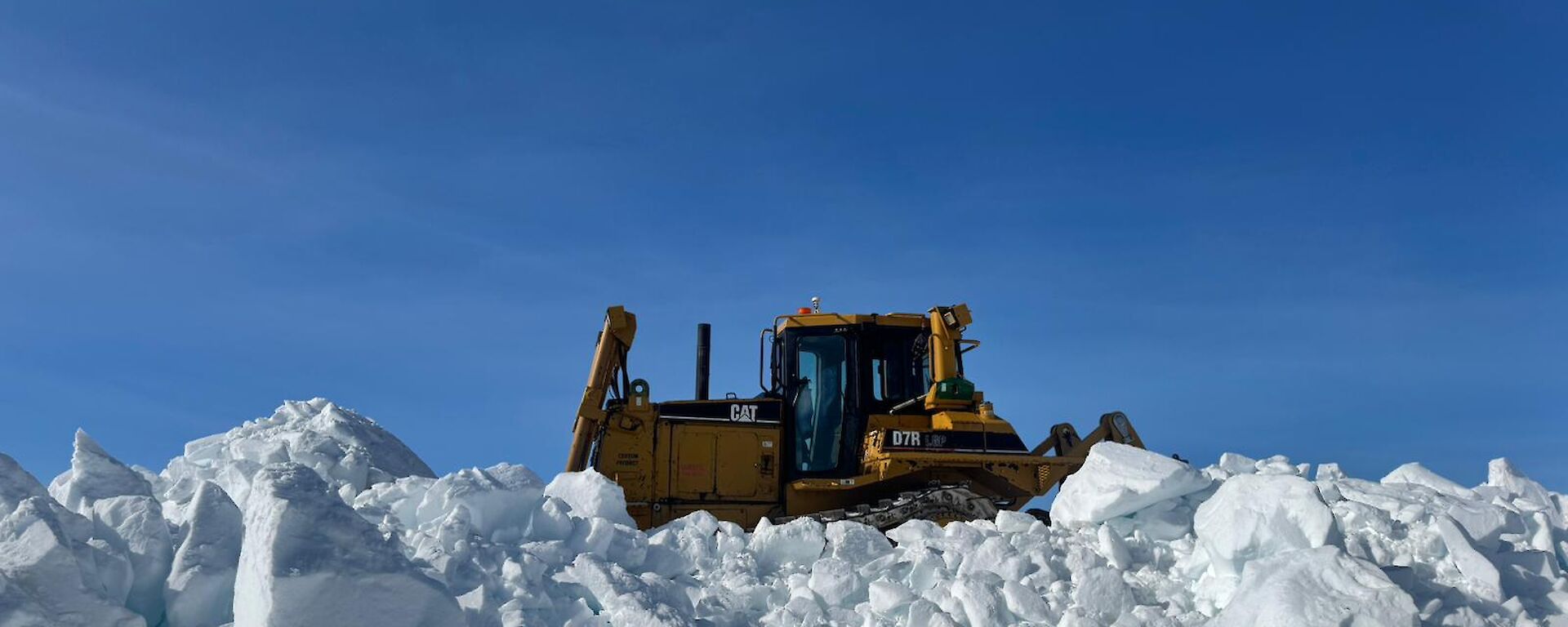 Dozer perched up on a snow berm cleairng snow