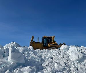 Dozer perched up on a snow berm cleairng snow