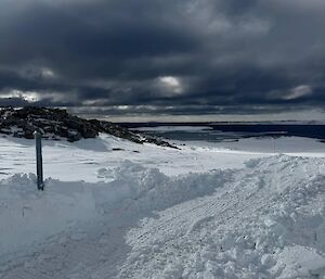 A snow-covered trail leading down to the ocean