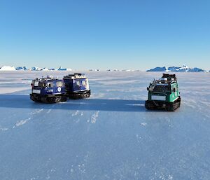 Two Hagglund vehicles parked side by side on a vast stretch of sea ice