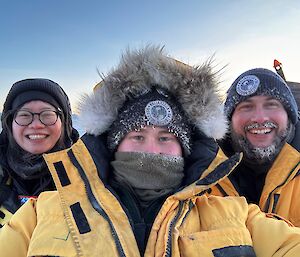 Selfie of three people in ice-covered headwear