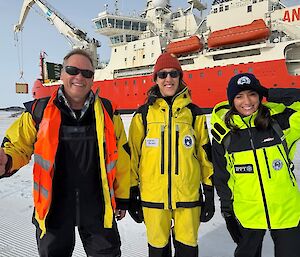 Three people in hi vis in front of an icebreaker