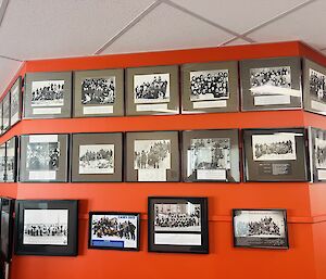 A red wall covered in framed team photos
