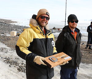 Two men standon a rocky hillside holding a oversized key