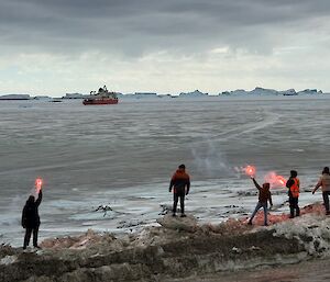 People on a rocky hillside setting off flares