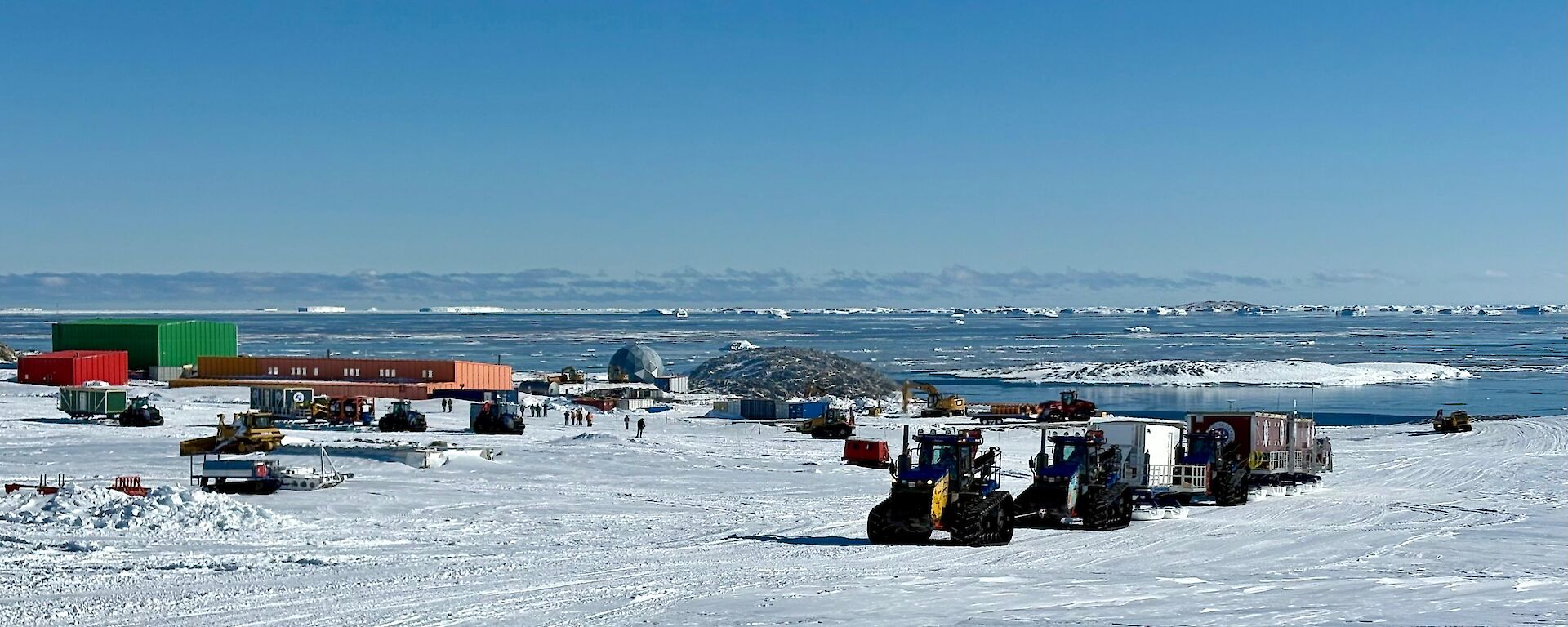 A tractor convoy towing sleds up a hill past Casey station.