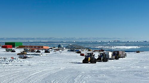 A tractor convoy towing sleds up a hill past Casey station.