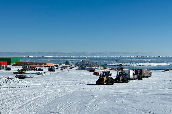 A tractor convoy towing sleds up a hill past Casey station.