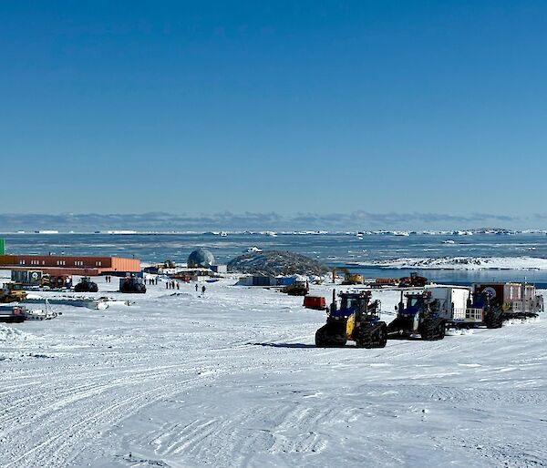 A tractor convoy towing sleds up a hill past Casey station.