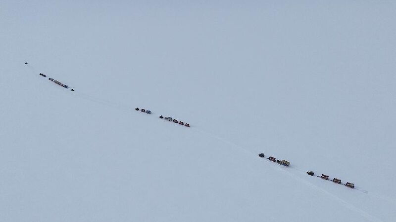 A distant aerial view of the tractor traverse snaking its way across a flat, white landscape