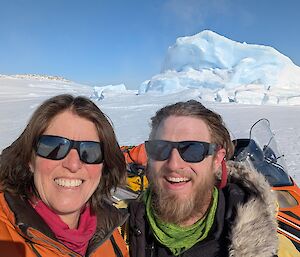 Two expeditioners smilling with snow and ice behind them