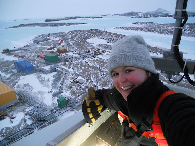 A woman taking in the view of Mawson station blanketed in snow, from a high vantage point.