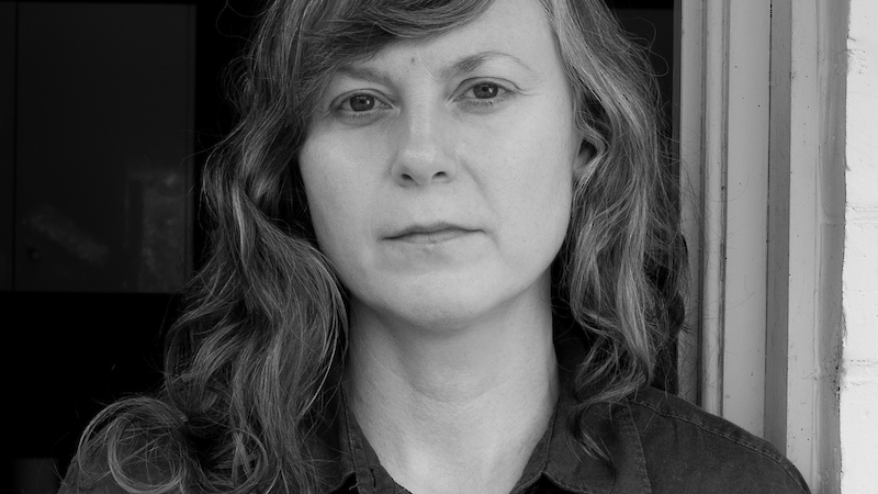 A woman stands leaning against a doorway