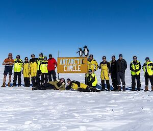 A group of expeditioners with a sign that read Antarctic Circle