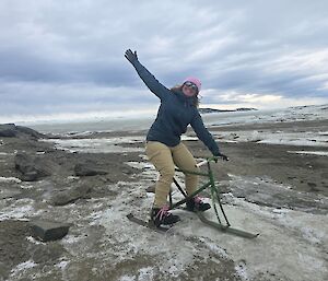 A woman celebrates on a 'ski bike' which is like a tricycle but with small skis in place of wheels