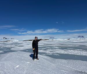 A person stands on ice with water around and points